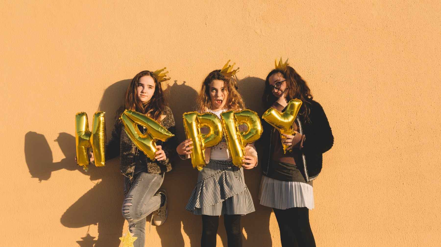 girls with happy writing foil balloons